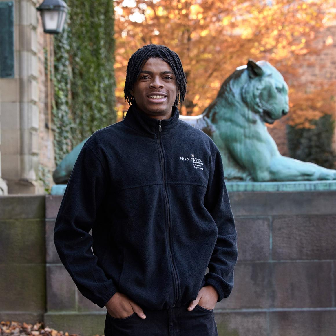 Terse Uppa Jr. stands in front of Nassau Hall, with the tiger statue behind him.